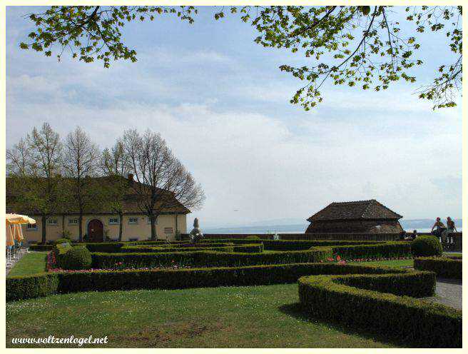 Jardins verdoyants et terrasses offrant une vue sur le lac et les Alpes.